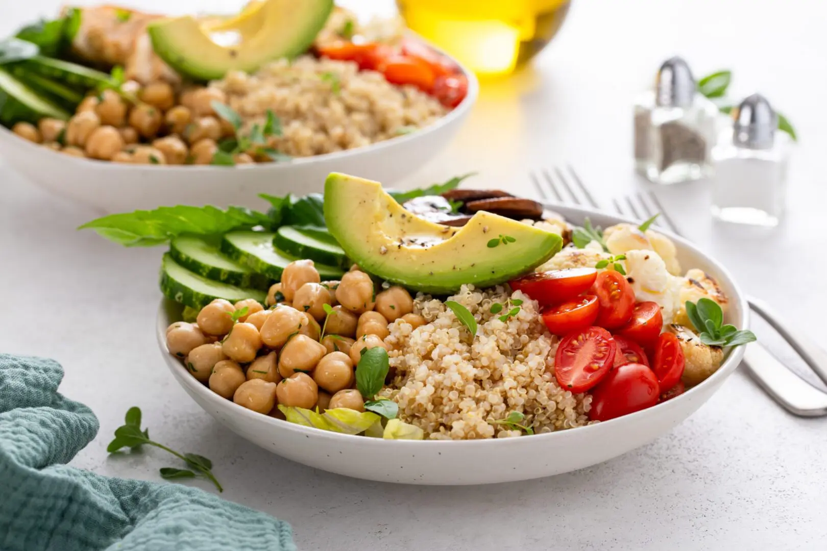 Two bowls of food on a table with forks.