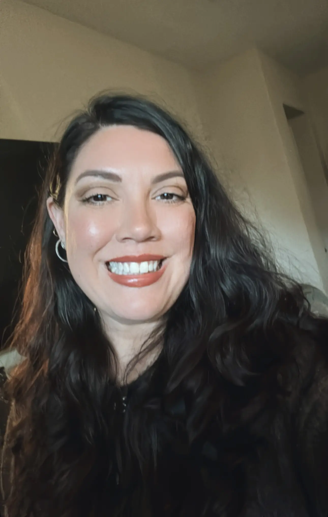 A woman with long black hair smiles for the camera.