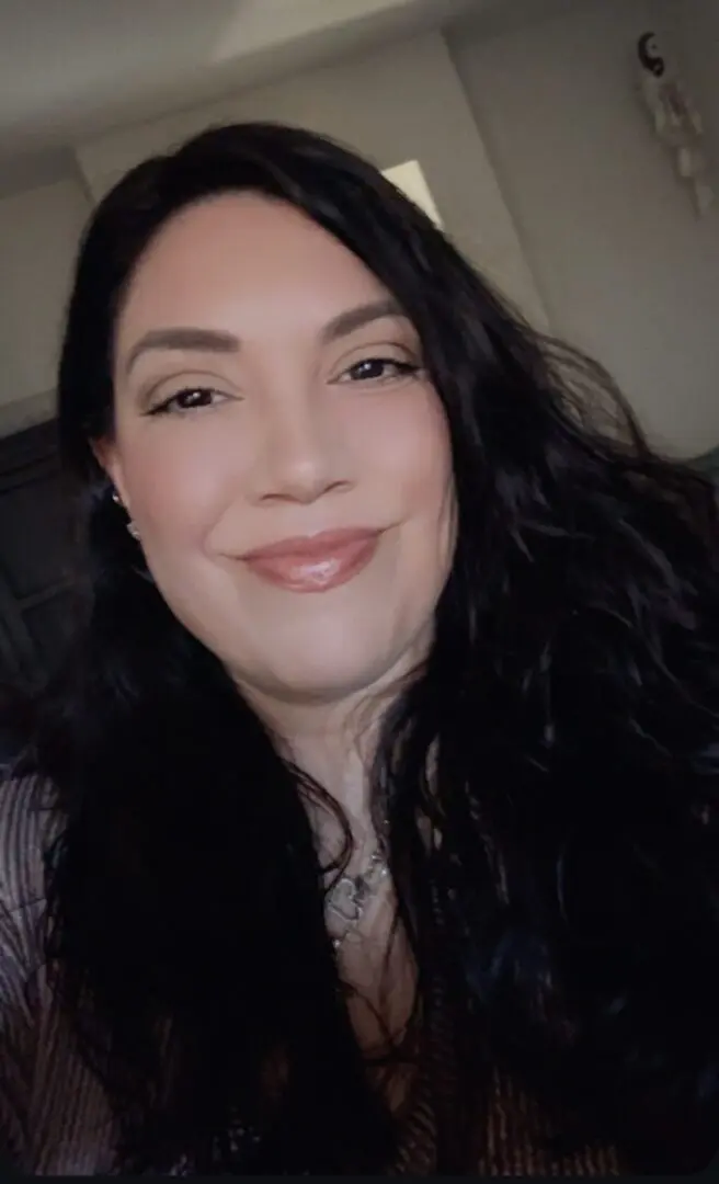 Screenshot A woman with long black hair smiles for the camera.