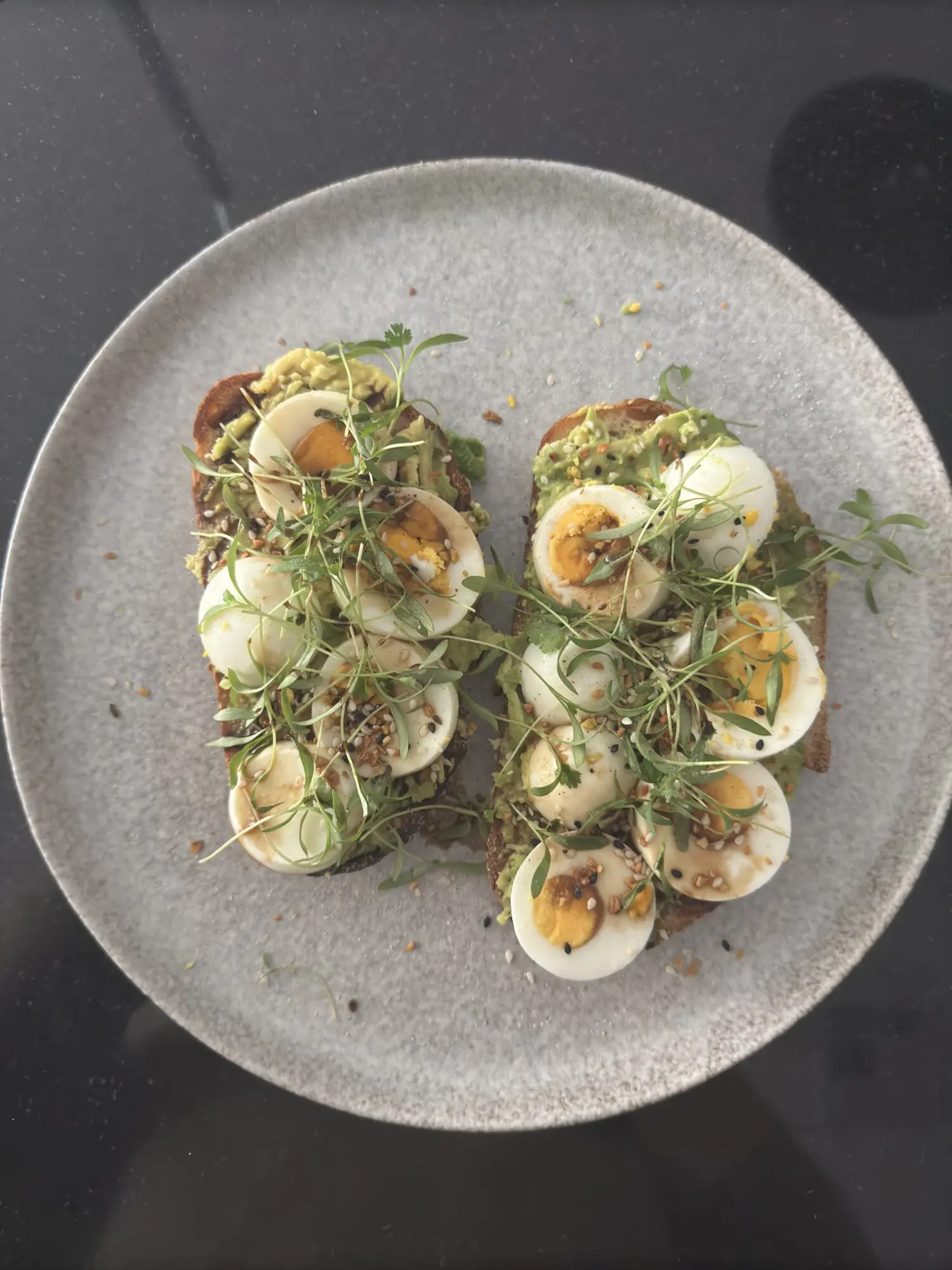 A plate with two pieces of bread topped with eggs and greens.